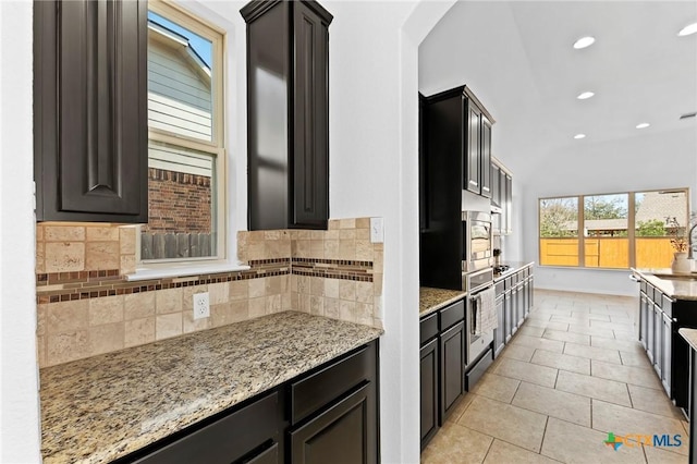 kitchen featuring tasteful backsplash, oven, light stone countertops, recessed lighting, and light tile patterned flooring