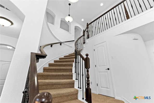 stairway featuring recessed lighting, baseboards, arched walkways, and carpet floors