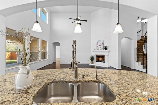 kitchen featuring plenty of natural light, stone countertops, ceiling fan, and a sink