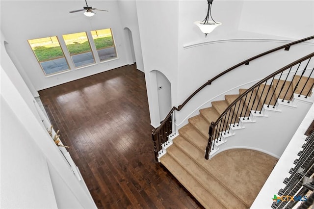 stairs featuring arched walkways, ceiling fan, and hardwood / wood-style flooring