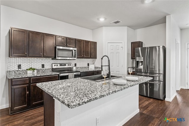 kitchen with sink, dark wood-type flooring, stainless steel appliances, and an island with sink