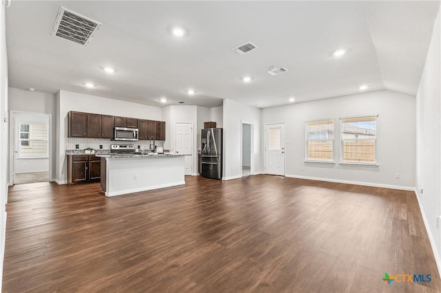 kitchen with appliances with stainless steel finishes, dark hardwood / wood-style floors, a wealth of natural light, and a center island with sink