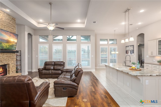 living room with a fireplace, light wood-type flooring, and ceiling fan