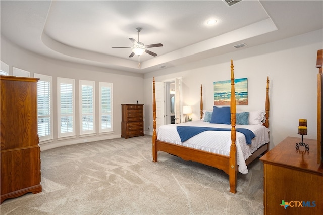 bedroom with a raised ceiling, ceiling fan, and carpet