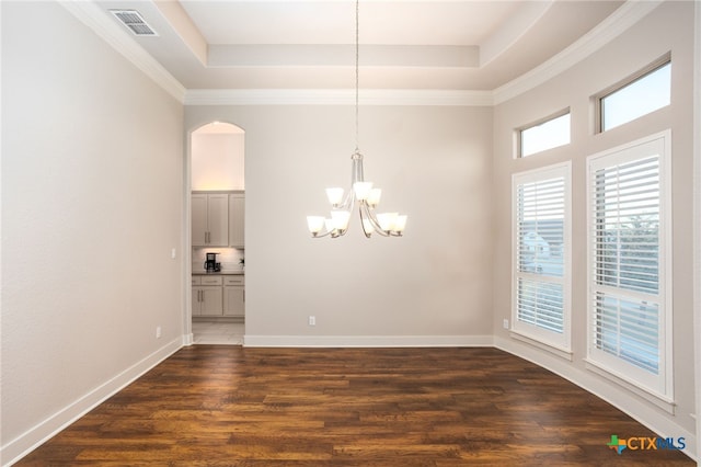 spare room featuring a tray ceiling, an inviting chandelier, dark wood-type flooring, and crown molding