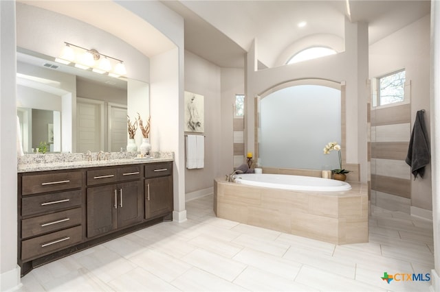 bathroom featuring tile patterned floors, tiled tub, and vanity