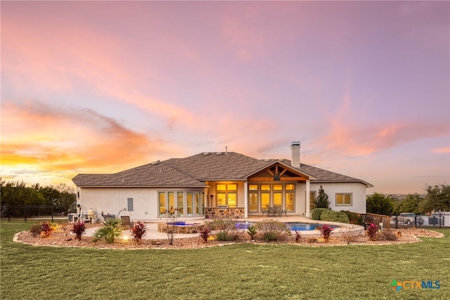 back house at dusk with a yard and a patio