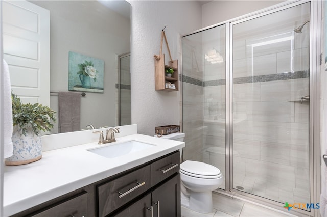 bathroom with tile patterned floors, a shower with door, vanity, and toilet