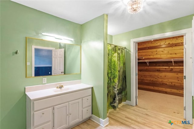 1200 4th St, Palacios, TX 77465 - bathroom featuring a stall shower, vanity, wood finished floors, a walk in closet, and baseboards