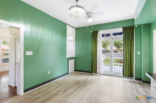 1200 4th St, Palacios, TX 77465 - empty room featuring wood finished floors, a ceiling fan, baseboards, and a chandelier
