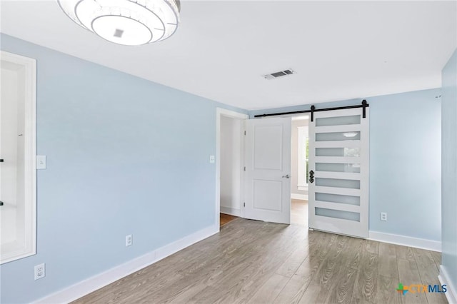 1200 4th St, Palacios, TX 77465 - empty room featuring a barn door, wood finished floors, and baseboards