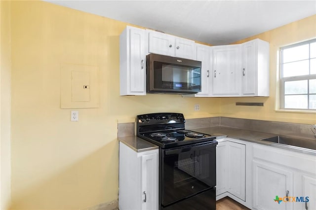 1200 4th St, Palacios, TX 77465 - kitchen featuring electric range, a sink, electric panel, and white cabinets