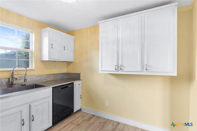 1200 4th St, Palacios, TX 77465 - kitchen with black dishwasher, a sink, white cabinetry, and light wood-style flooring