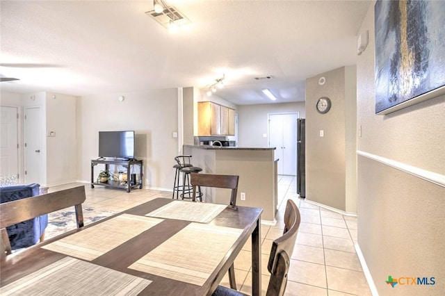 dining area with track lighting and light tile patterned floors