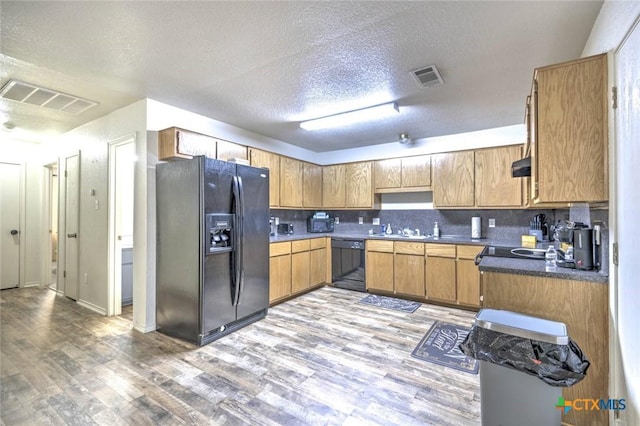 kitchen with a textured ceiling, light hardwood / wood-style floors, black appliances, and decorative backsplash