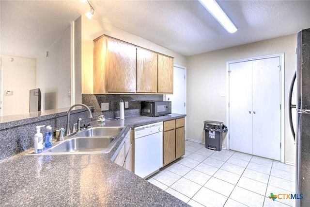 kitchen with light tile patterned floors, black appliances, tasteful backsplash, rail lighting, and sink