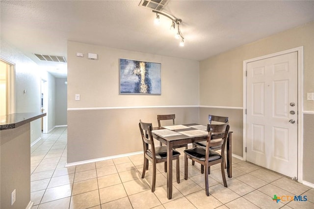 dining space featuring rail lighting, a textured ceiling, and light tile patterned floors