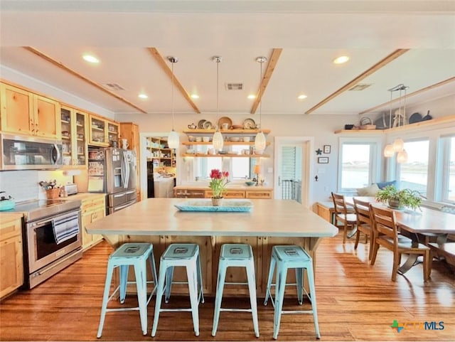 kitchen featuring pendant lighting, a kitchen island, a kitchen breakfast bar, and appliances with stainless steel finishes