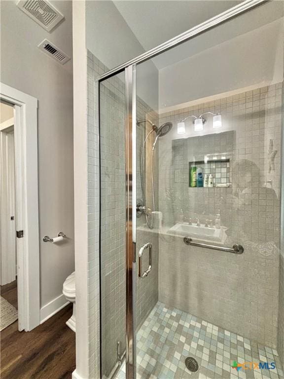 bathroom with hardwood / wood-style flooring, toilet, sink, and a shower with shower door