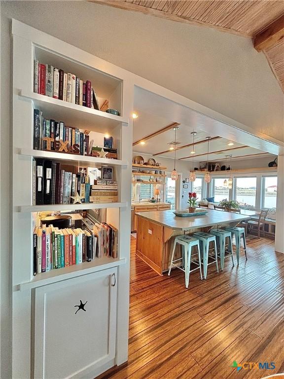 kitchen featuring decorative light fixtures, a center island, beam ceiling, and light hardwood / wood-style flooring