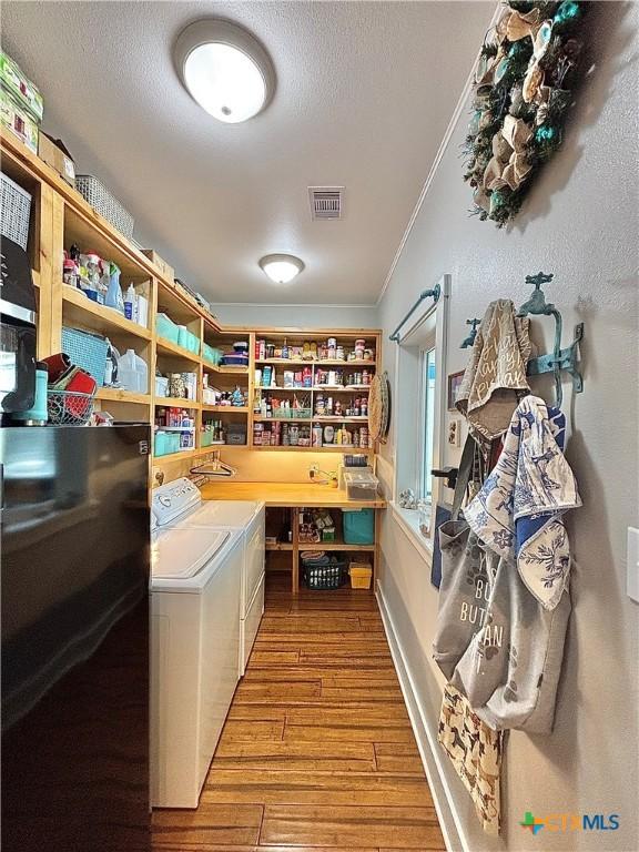 interior space featuring separate washer and dryer, crown molding, a textured ceiling, and light wood-type flooring