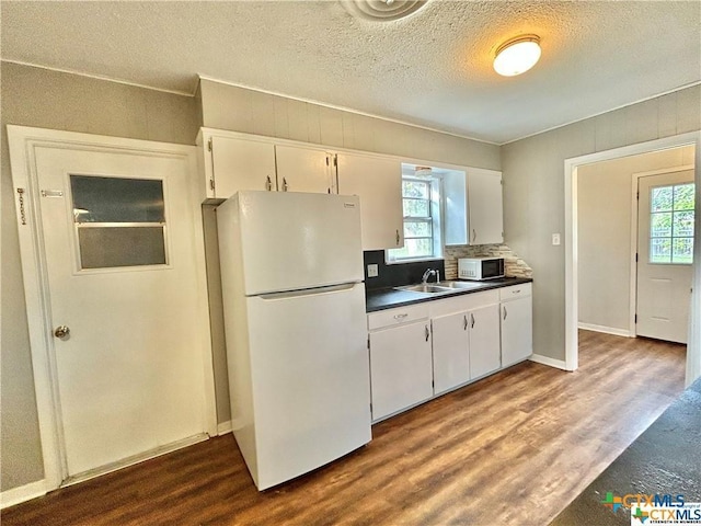 kitchen featuring dark wood-type flooring, white appliances, a healthy amount of sunlight, and a sink