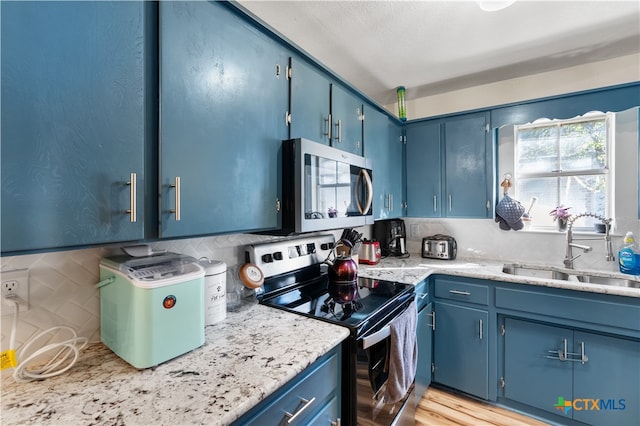 kitchen featuring sink, light hardwood / wood-style flooring, blue cabinetry, tasteful backsplash, and stainless steel appliances