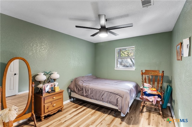 bedroom with wood-type flooring, a textured ceiling, and ceiling fan