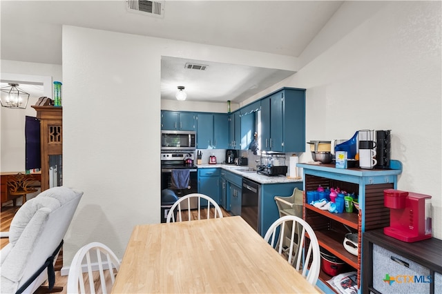 kitchen featuring stainless steel appliances, blue cabinets, sink, a chandelier, and hardwood / wood-style floors