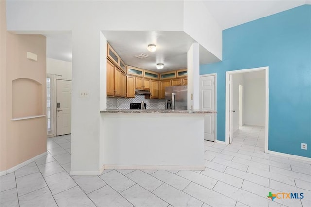 2991 Lakeview E Dr, Ingleside, TX 78362 - kitchen with stainless steel fridge, light countertops, backsplash, baseboards, and under cabinet range hood