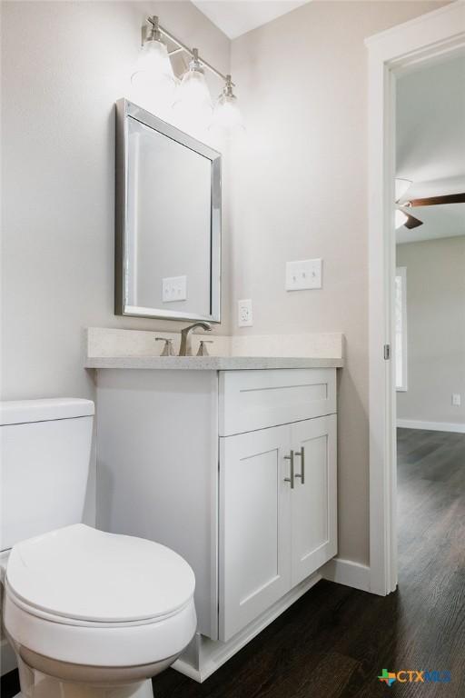 801 E Morgan Ave, Cuero, TX 77954 - half bathroom with vanity, wood finished floors, toilet, and ceiling fan