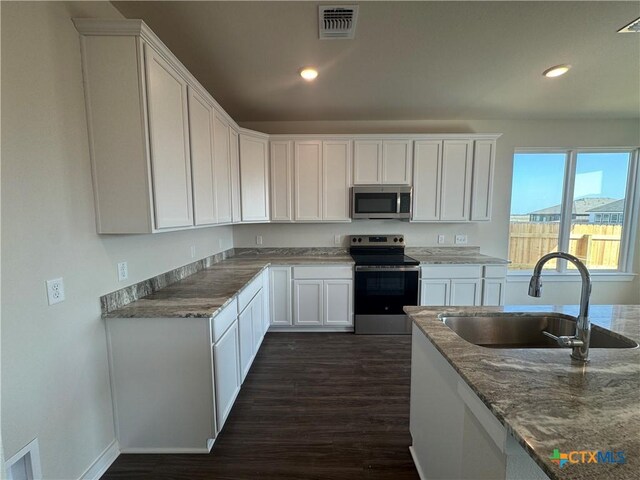 kitchen with visible vents, open floor plan, dark wood finished floors, appliances with stainless steel finishes, and white cabinets