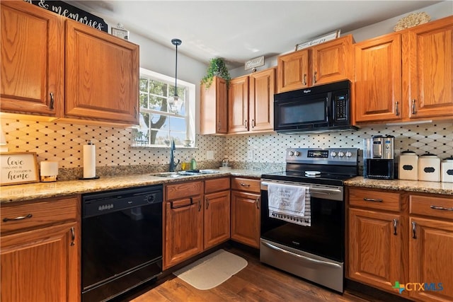 kitchen with brown cabinetry, dark wood-style flooring, hanging light fixtures, black appliances, and a sink