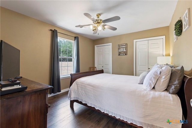 bedroom with multiple closets, dark wood-style flooring, ceiling fan, and baseboards