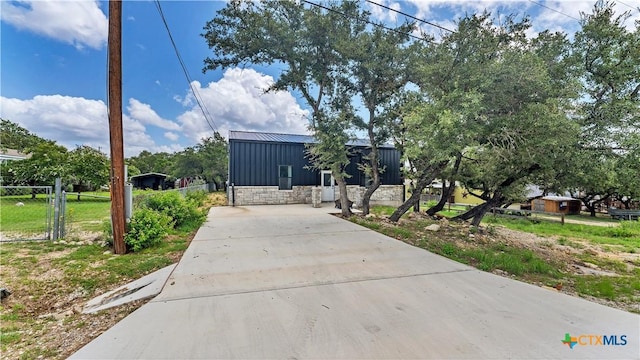 view of front facade featuring board and batten siding, fence, driveway, and metal roof
