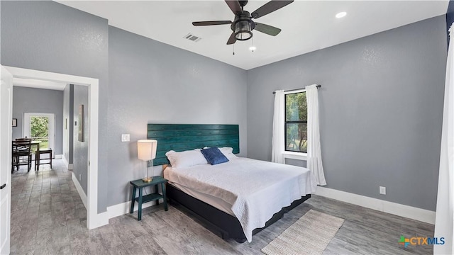 bedroom featuring visible vents, baseboards, wood finished floors, and multiple windows