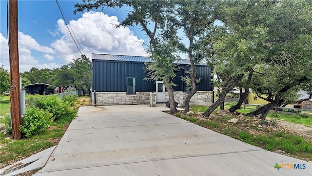 exterior space with board and batten siding, fence, stone siding, and metal roof