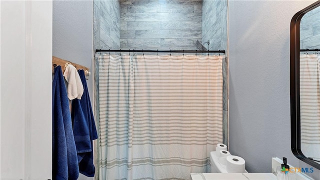 full bathroom featuring a textured wall, curtained shower, and toilet