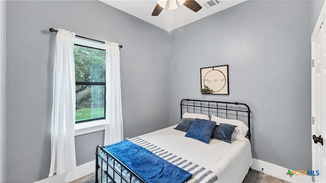 bedroom with a ceiling fan, baseboards, visible vents, and wood finished floors