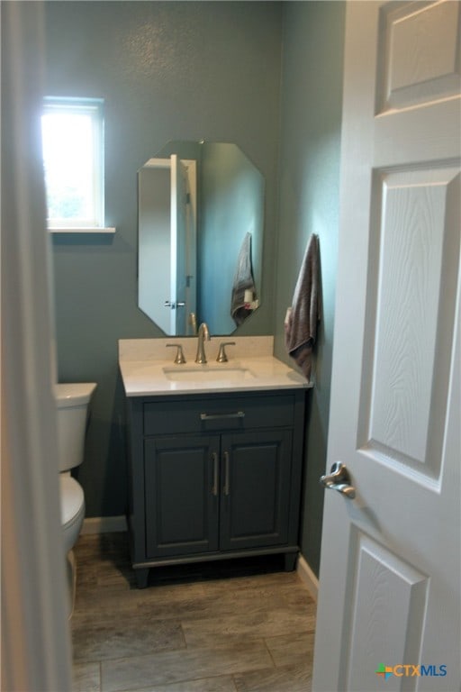 bathroom featuring toilet, vanity, and wood-type flooring