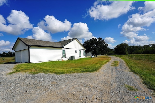 view of property exterior with central AC unit, a garage, and a lawn