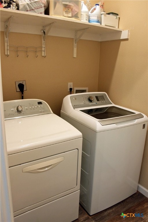 clothes washing area with dark hardwood / wood-style floors and washer and dryer