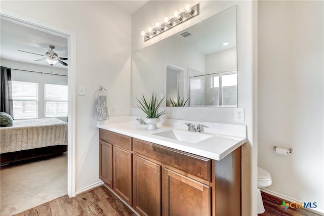 bathroom with ceiling fan, vanity, wood-type flooring, a shower with shower door, and toilet