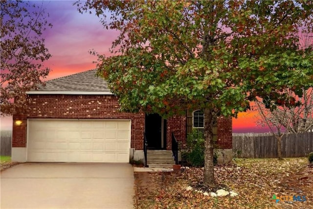 obstructed view of property with brick siding, roof with shingles, an attached garage, fence, and driveway