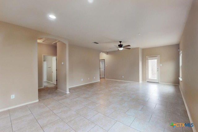 spare room with arched walkways, visible vents, ceiling fan, and baseboards