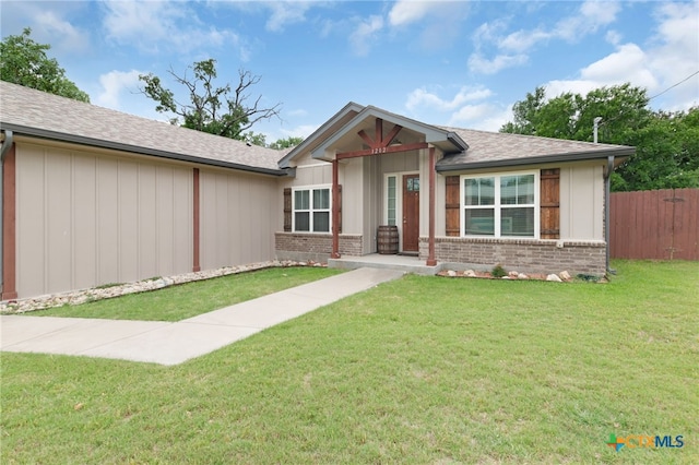 view of front of house with brick siding, fence, and a front lawn