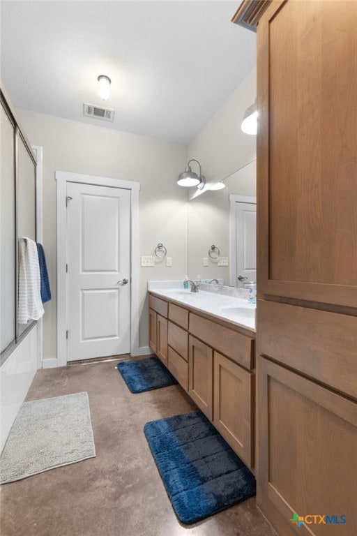 full bath featuring double vanity, combined bath / shower with glass door, visible vents, and a sink