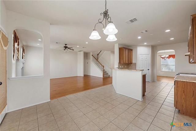 125 Big Timber Dr, Temple, TX 76502 - kitchen featuring a chandelier, light tile patterned floors, arched walkways, a ceiling fan, and brown cabinets
