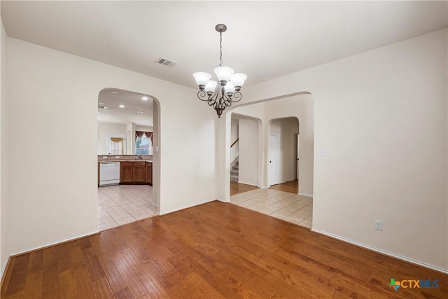 125 Big Timber Dr, Temple, TX 76502 - spare room with light wood finished floors, arched walkways, a chandelier, and stairway