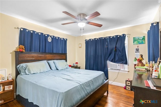 bedroom with cooling unit, wood finished floors, baseboards, and ceiling fan